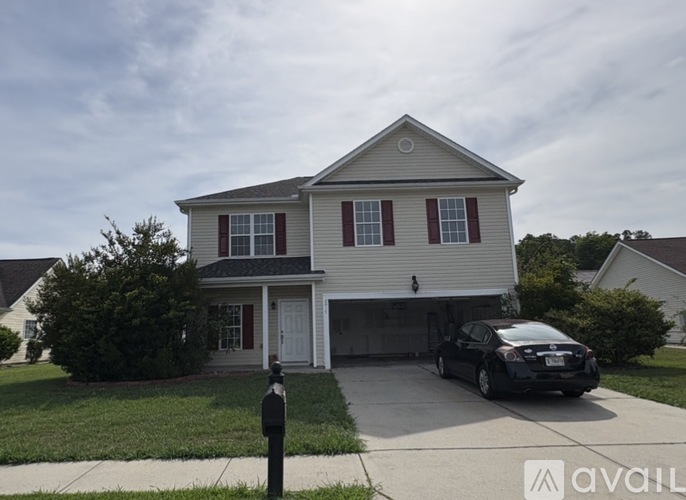 A two-story house with a garage and a car parked in front.
