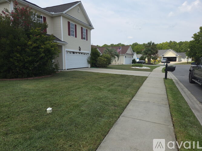 A house with a white garage door is surrounded by green grass and a sidewalk.