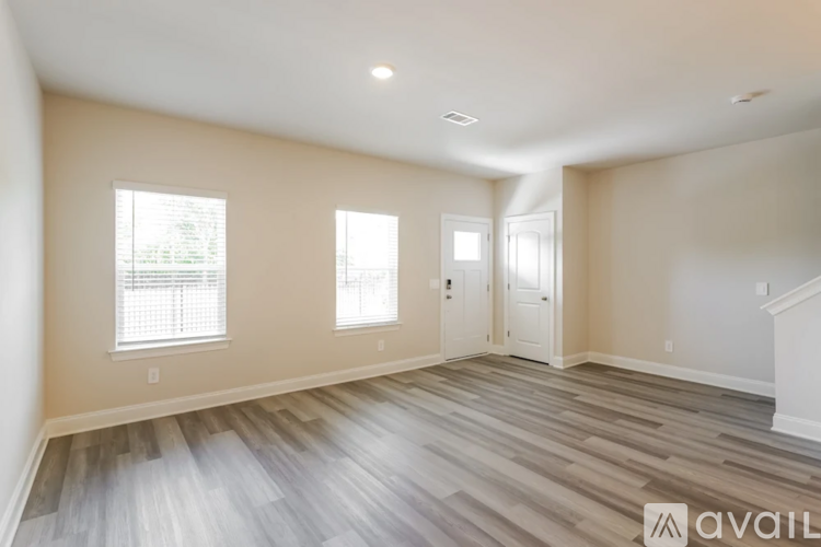 A spacious room with wooden flooring and white walls.