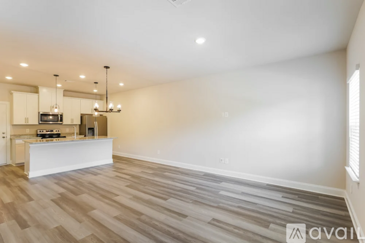 A spacious living room with a kitchen area in the background.