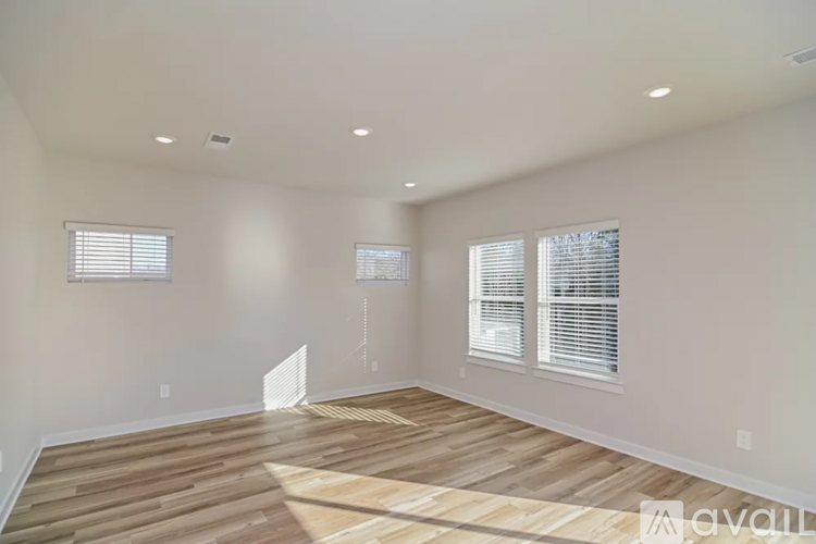 A spacious room with wooden flooring and white walls.