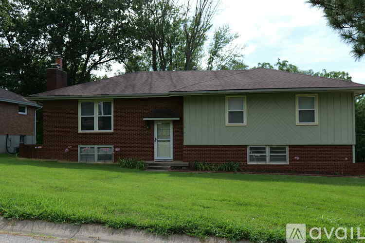 A house with a red brick exterior and a green siding is for sale.