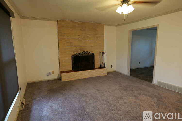 A living room with a fireplace and a ceiling fan.