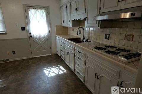 A kitchen with white cabinets and a tiled floor.