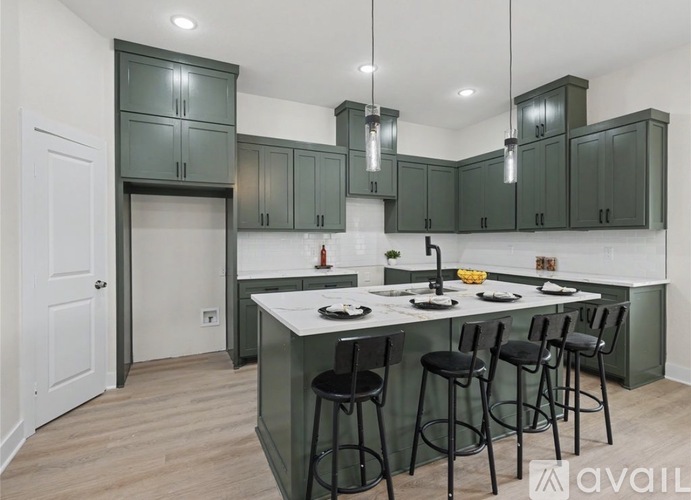 A kitchen with green cabinets and a white island.