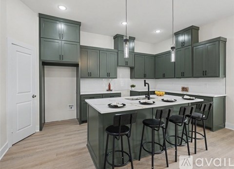 A kitchen with green cabinets and a white island.