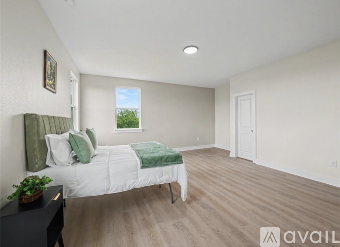 A bedroom with a bed, nightstand, and window.