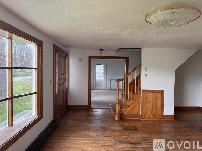A room with wooden floors and a staircase leading to another room.