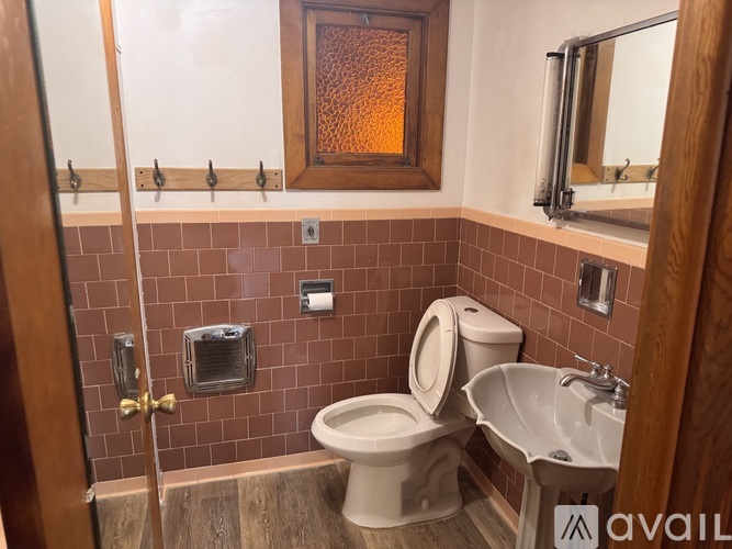 A bathroom with a toilet, sink, and mirror.