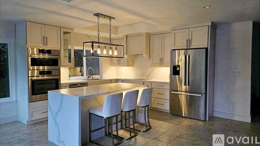 A modern kitchen with a marble island and stainless steel appliances.