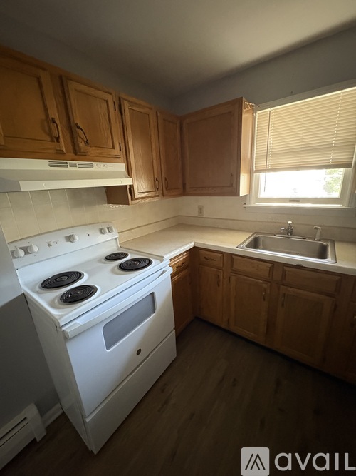 A kitchen with wooden cabinets and a white stove top oven.
