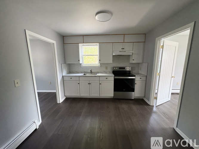 A kitchen with white cabinets and a wooden floor.