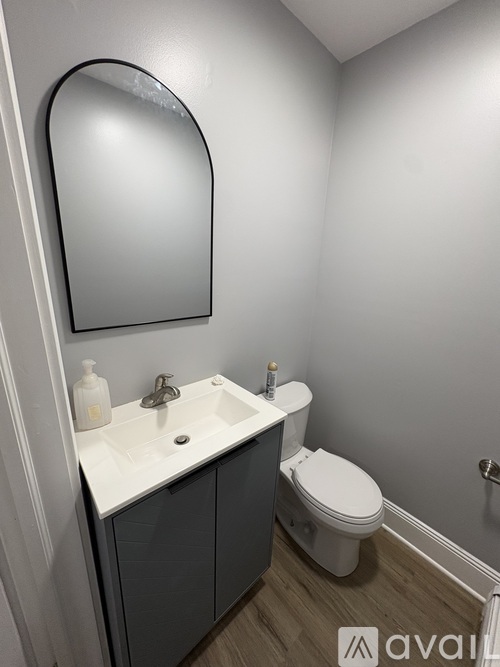 A bathroom with a sink, toilet and mirror.