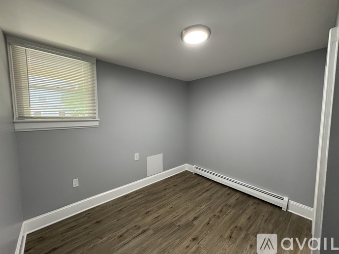 A room with wooden flooring and a window with blinds.