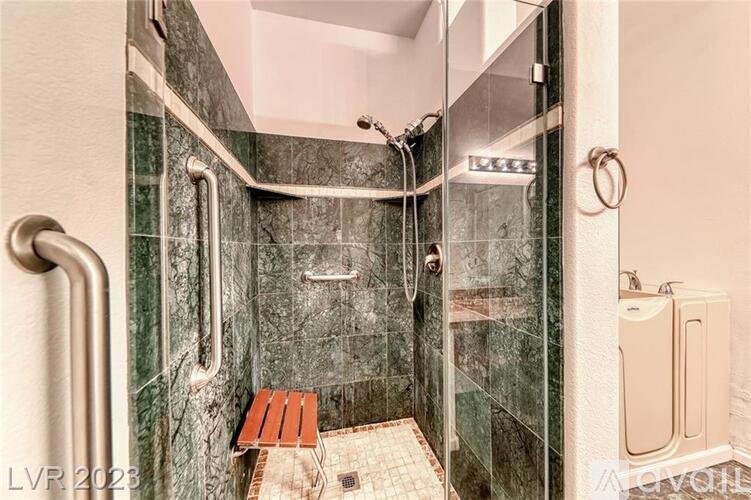 A modern bathroom with a glass shower stall and a bench.