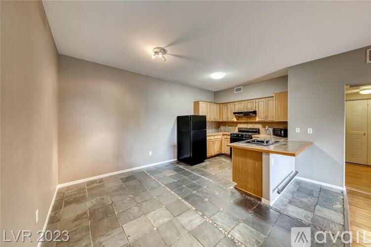 A kitchen with a black refrigerator and wooden cabinets.