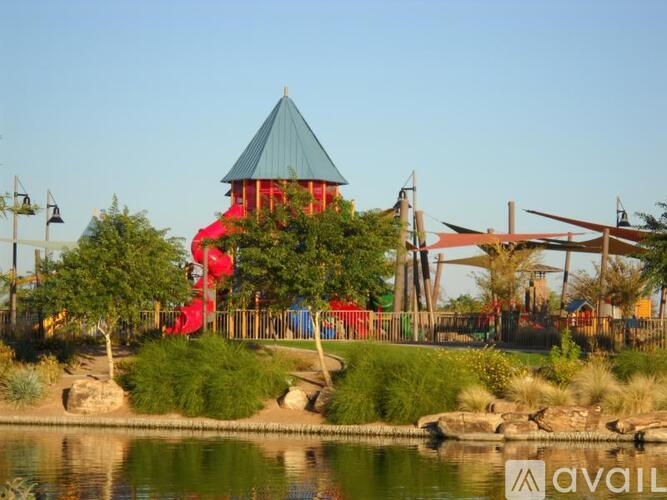 A playground with a red slide and a green roofed structure.