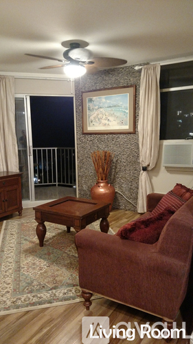 A brown couch sits in a living room with a painting on the wall.