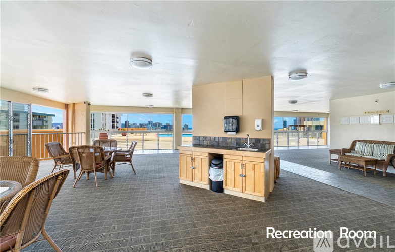 A spacious recreation room with a kitchenette and a view of the pool.