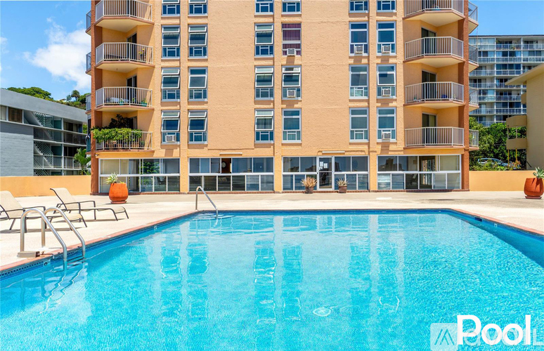 A large swimming pool in front of a multi-story apartment building.