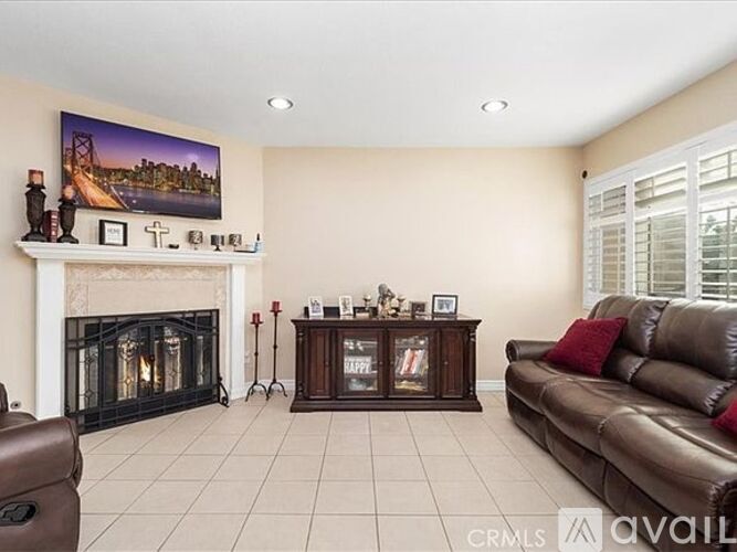 A living room with a fireplace, a couch, and a painting of a bridge on the wall.