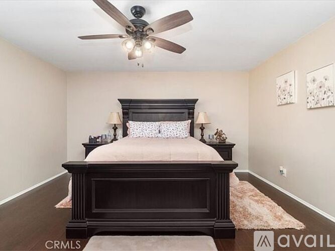 A bedroom with a large bed and a ceiling fan.