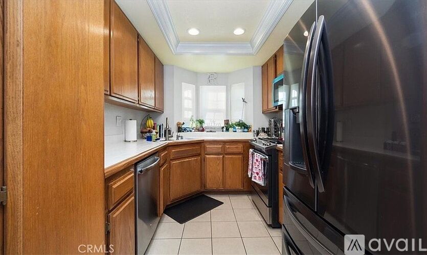 A kitchen with wooden cabinets and a black refrigerator.