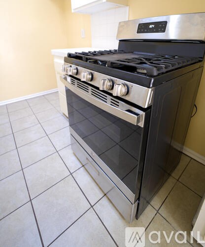 A black stove top oven in a kitchen with tile flooring.