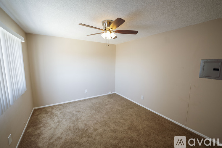 A room with a ceiling fan and carpeted floor.