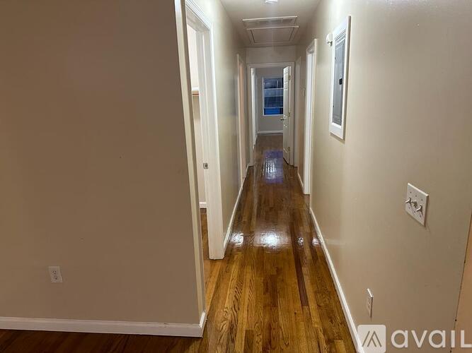 A long hallway with wood floors and white walls.