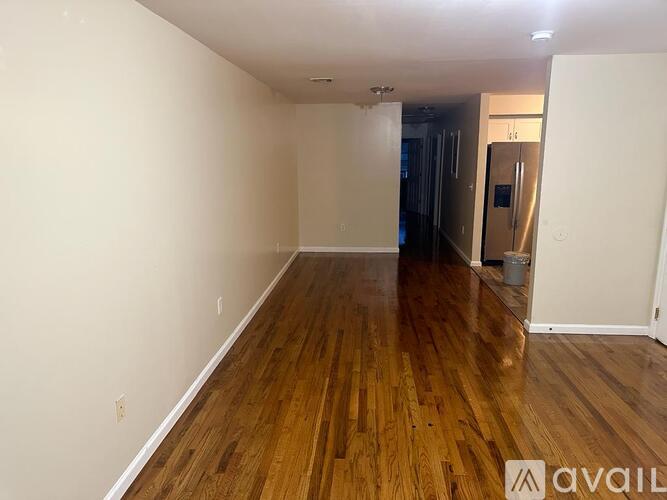A room with wooden floors and white walls is available for rent.