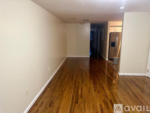 A room with wooden floors and white walls is available for rent.