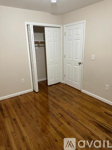 A room with a white door and a wooden floor.