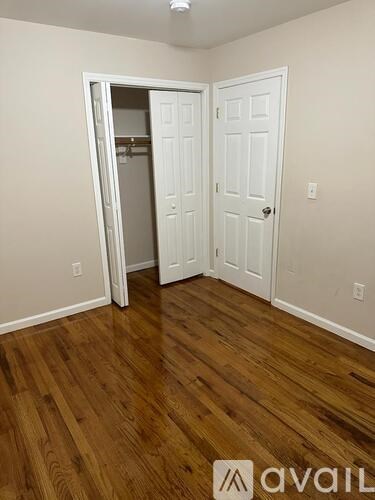 A room with a white door and a wooden floor.