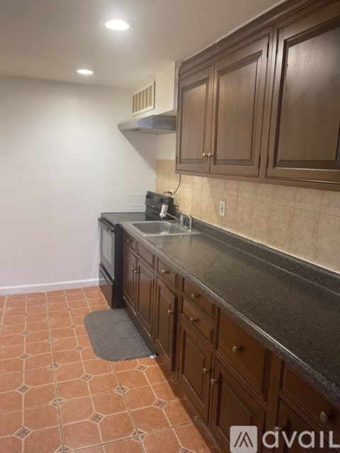 A kitchen with brown cabinets and a black countertop.