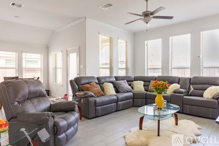 A living room with a grey sofa set and a glass coffee table.