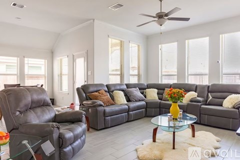 A living room with a grey sofa set and a glass coffee table.