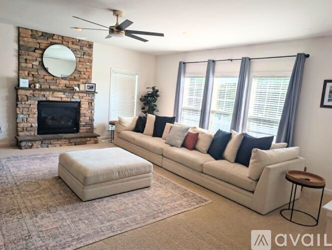 A living room with a stone fireplace and a white couch.