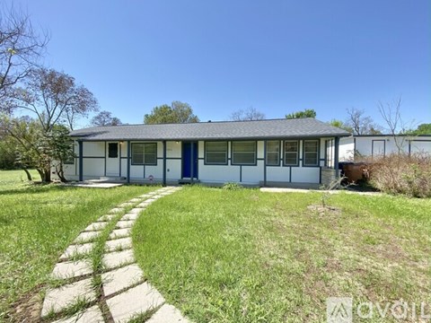 A house with a blue door and windows is surrounded by a grassy area.