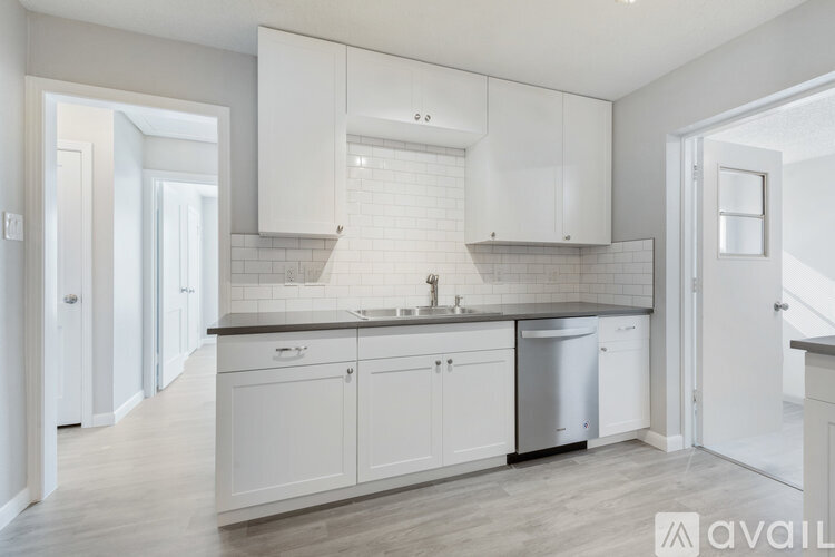 A kitchen with white cabinets and a black countertop.