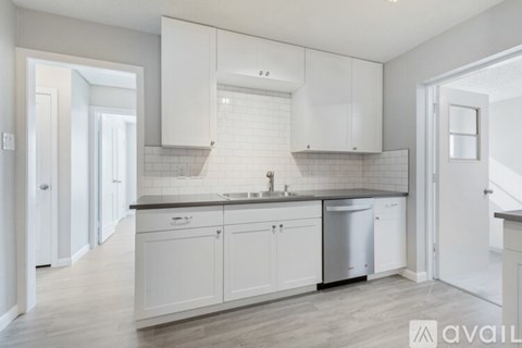 A kitchen with white cabinets and a black countertop.