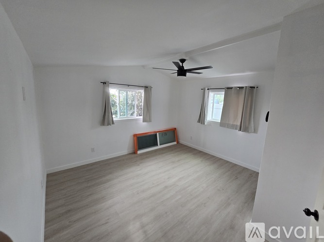 A room with a ceiling fan and two windows.