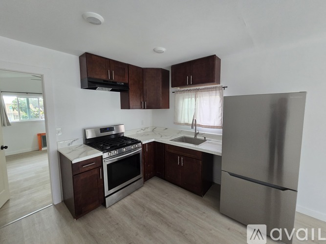 A kitchen with a stove, sink, and refrigerator.