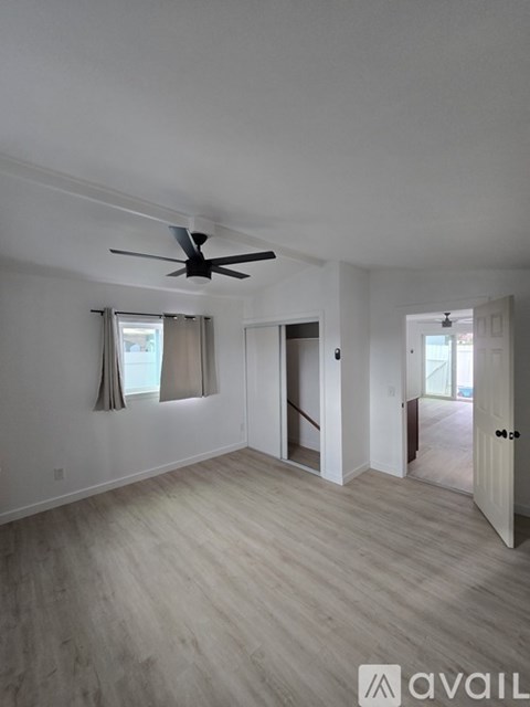 A spacious room with a ceiling fan and light wood flooring.