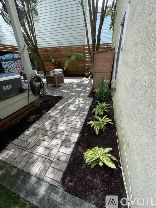 A patio with a brick patterned walkway and a few plants.