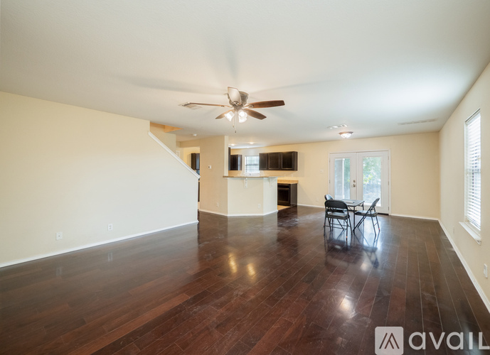 A spacious room with wood flooring and a ceiling fan.
