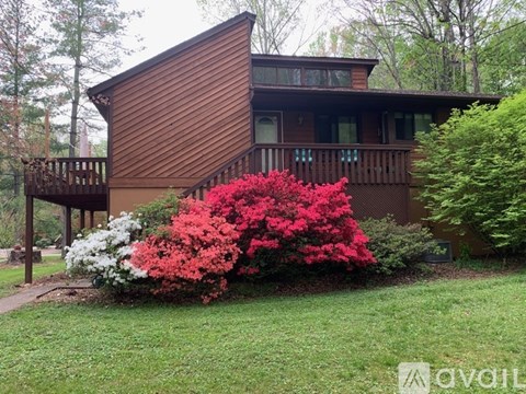 A house with a red flowering bush in front.