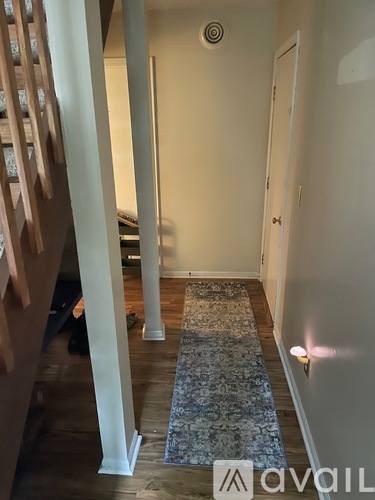 A hallway with a rug and a door on the right.