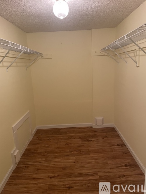 Empty walk-in closet with white shelves and wooden floors.