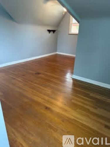 A room with wooden flooring and a white wall.